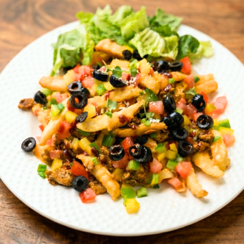 Low FODMAP loaded nacho fries topped with seasoned ground meat, melted cheese, black olives, tomato, and green onion tops
